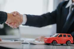 握手をする人たちの前に置かれた車の模型