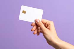 紫の背景の前で白いカードを持つ手