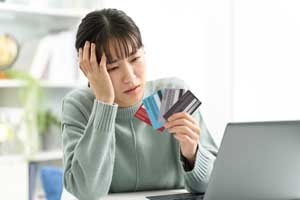 複数のカードを手に悩む女性